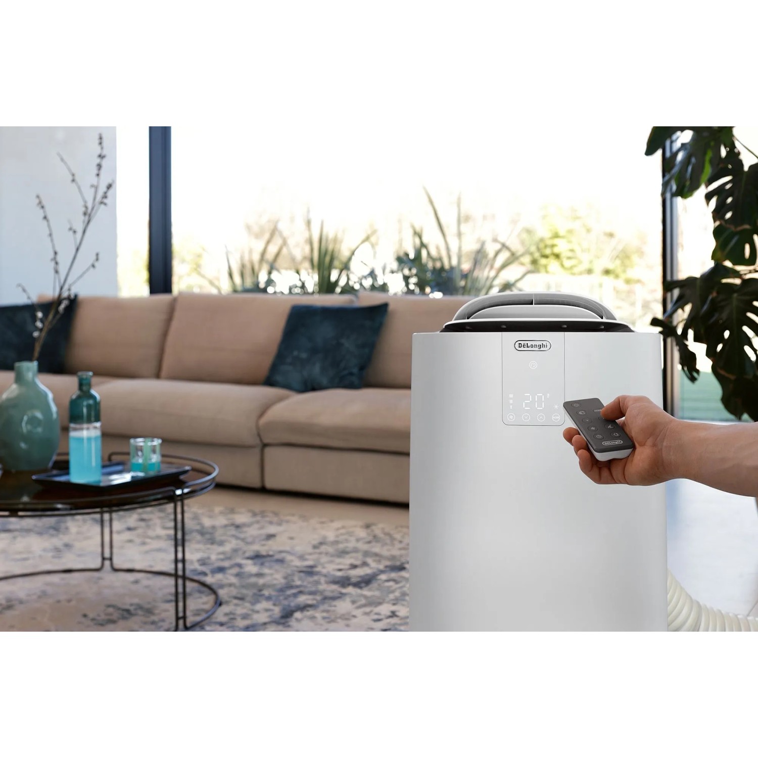 Weißes De'Longhi Klimagerät PAC-AP140i im Wohnraum mit Fernbedienung.