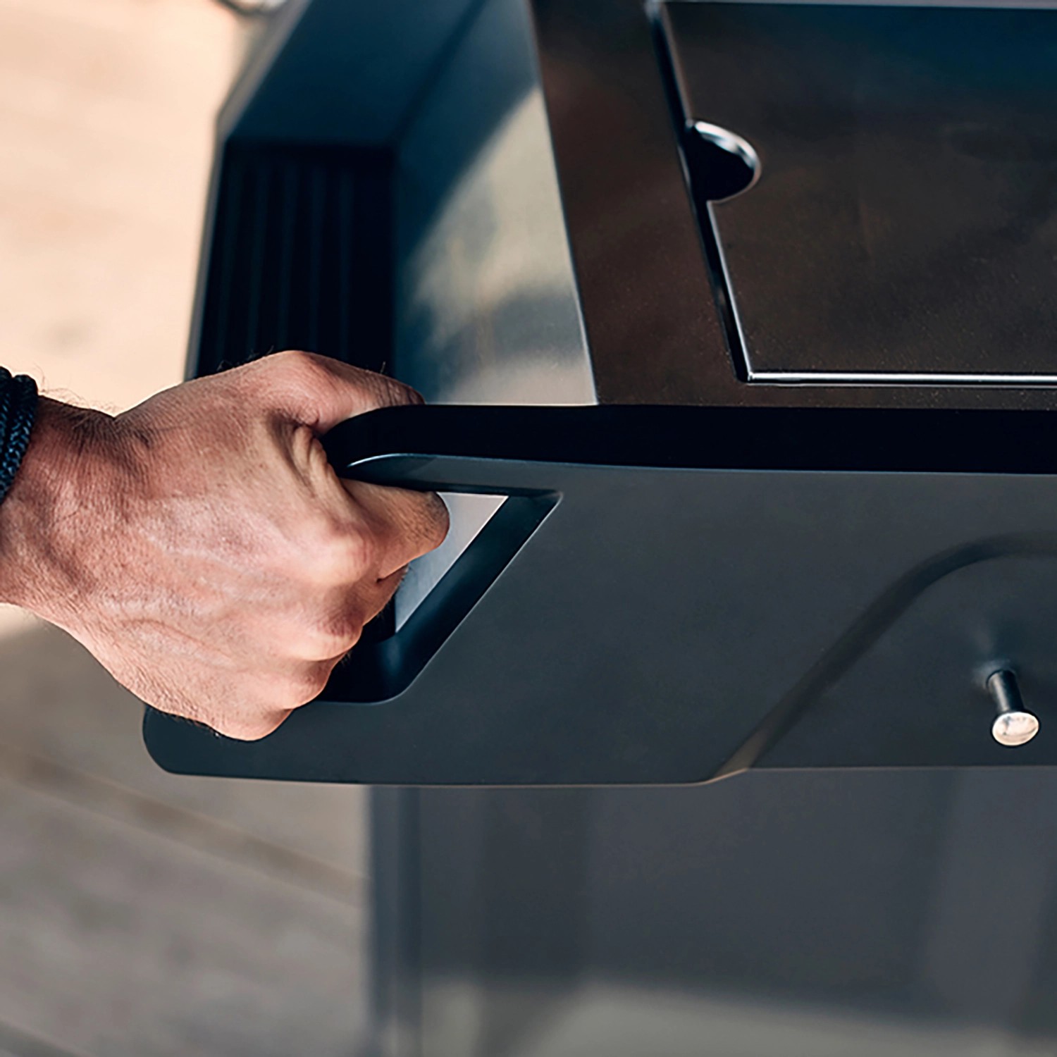 Detailaufnahme: Hand öffnet Seitenablage des Enders Gasgrills Monroe Pro 4 SIK Turbo.