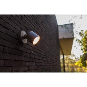 Lutec LED-Außenwandspot Explorer an dunkler Backsteinwand. Schwenkbare Außenleuchte mit warmweißem Licht.