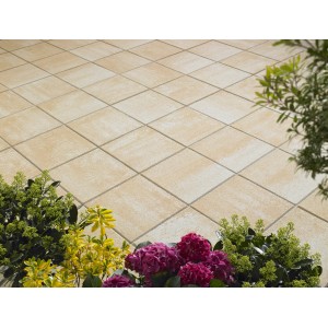 Verona Terrassenplatten in Sandsteingelb-Nuanciert, 40x40 cm, auf einer Terrasse mit Blumen.