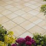 Verona Terrassenplatten in Sandsteingelb-Nuanciert, 40x40 cm, auf einer Terrasse mit Blumen.