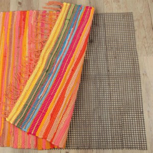 Dunkelgrauer ProHome Teppich Gleitschutz 80x120 cm unter bunten Teppichen auf Holzboden.
