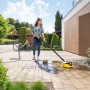 Frau reinigt Pflaster mit Kärcher Flächenreiniger T 5 T-Racer im Garten.