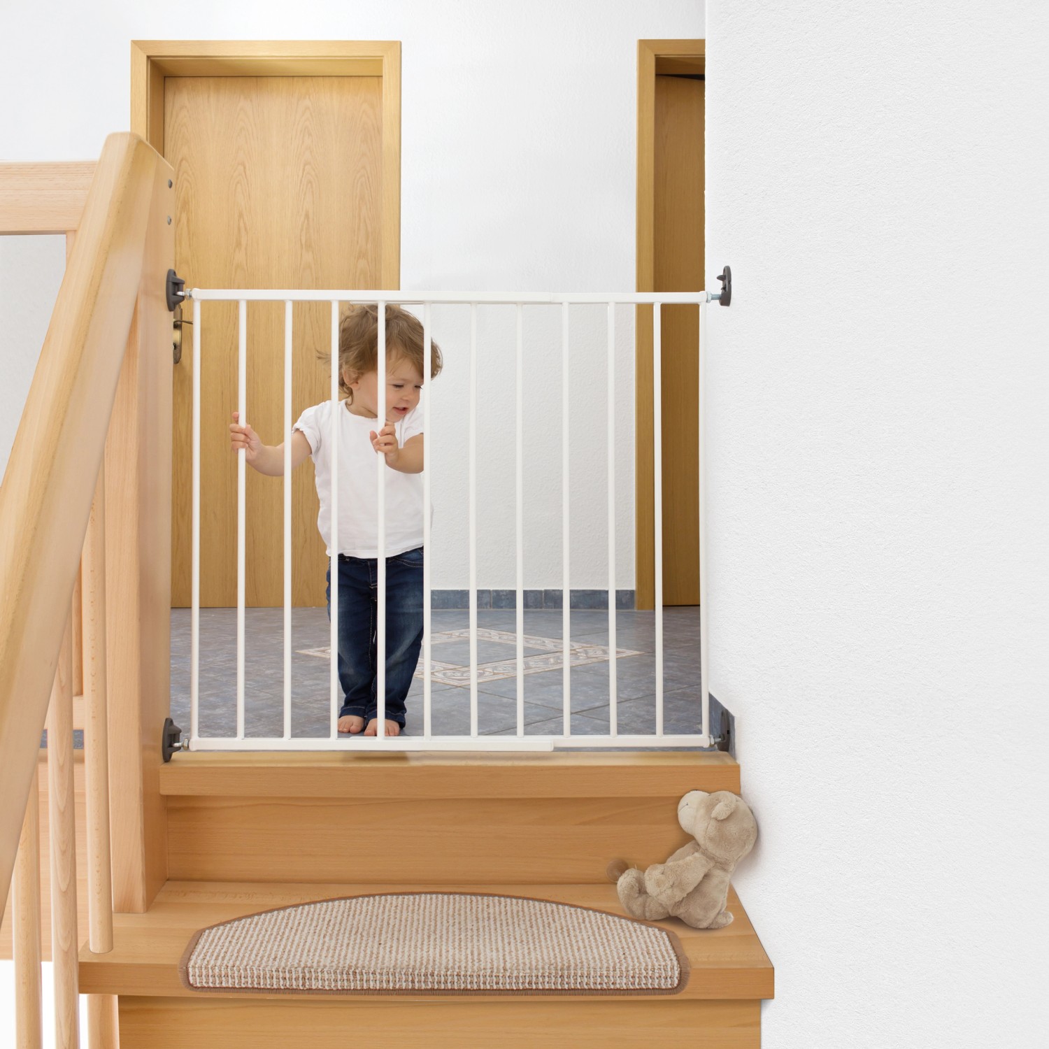 Weißes Schraubgitter Simple-Lock sichert Treppe; Kind steht davor. Türschutzgitter für Kinder.