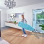Frau trägt Leifheit Bügeltisch AirBoard Compact M Plus mit blauem Bezug. Höhenverstellbares Bügelbrett mit Thermo-Reflect Bezug.
