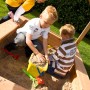 Kinder spielen im Sandkasten des Axi Sarah Spielhauses (braun/grün) mit Sandspielzeug.