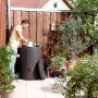 Garantia Regenspeicher Timber 230 l in Braun mit Person beim Gießen im Garten.