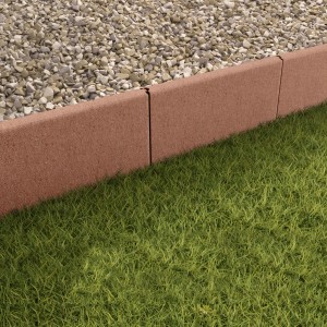 Braune, abgerundete Rasenkantensteine aus Beton als Beetbegrenzung im Garten.