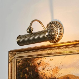 Antike Wandleuchte Joely in Bronze über einem Gemälde. Retro Wandlampe für Innenräume.