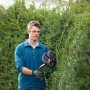 Mann schneidet Hecke mit Bosch Akku-Heckenschere Universal Hedge Cut 18-55.