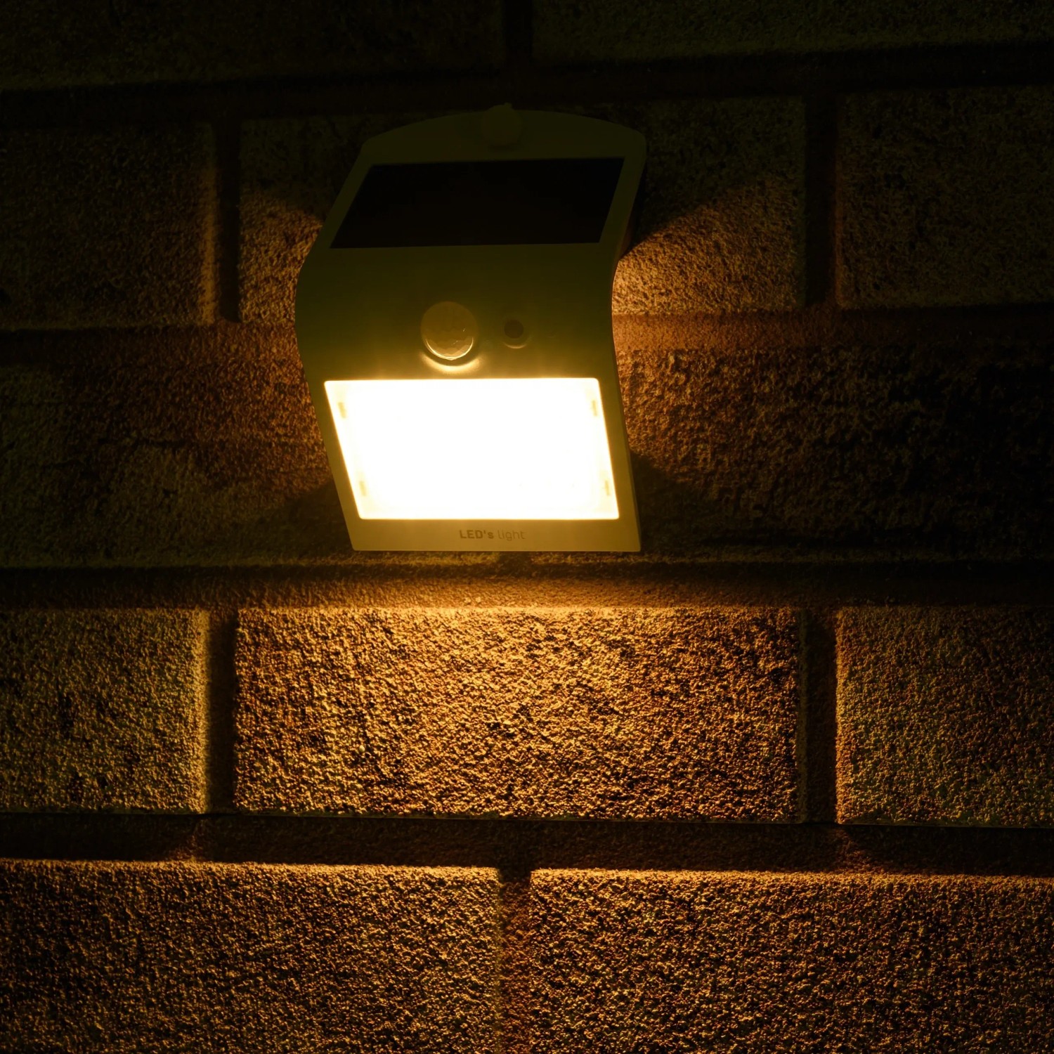 Weiße LED's Work Solar-Außenleuchte mit Sensor an einer Backsteinwand.