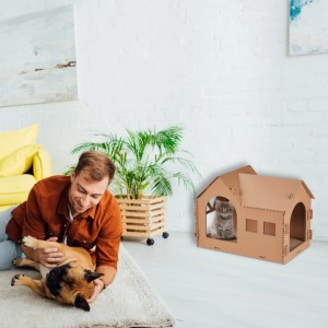 Braunes Relaxdays Katzenhaus aus Pappe mit Kratzbrett, im Landhausstil. Katze sitzt im Haus, Mann spielt mit Hund.