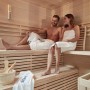 Paar entspannt in der SKYLINE BIG Sauna aus Tannenholz. Holzverkleidung und Bänke sichtbar.