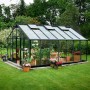 Juliana Gewächshaus Gärtner 18 Anthrazit mit Pflanzen und Gartenmöbeln im Garten.