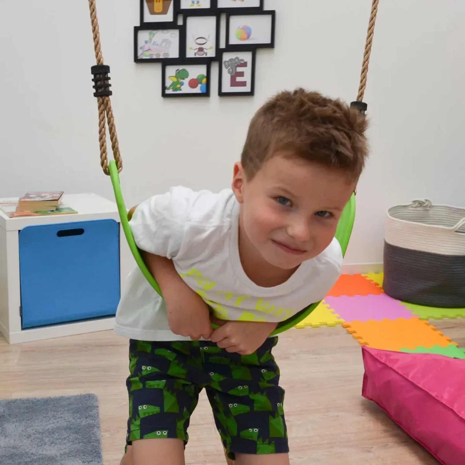 Kind auf grüner LittleTom Brettschaukel. Die Schaukel ist bis 100 kg belastbar.