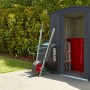 Globel Metall-Gerätehaus Dream 65 in Anthrazit mit Schubkarre und Gartenschlauch.