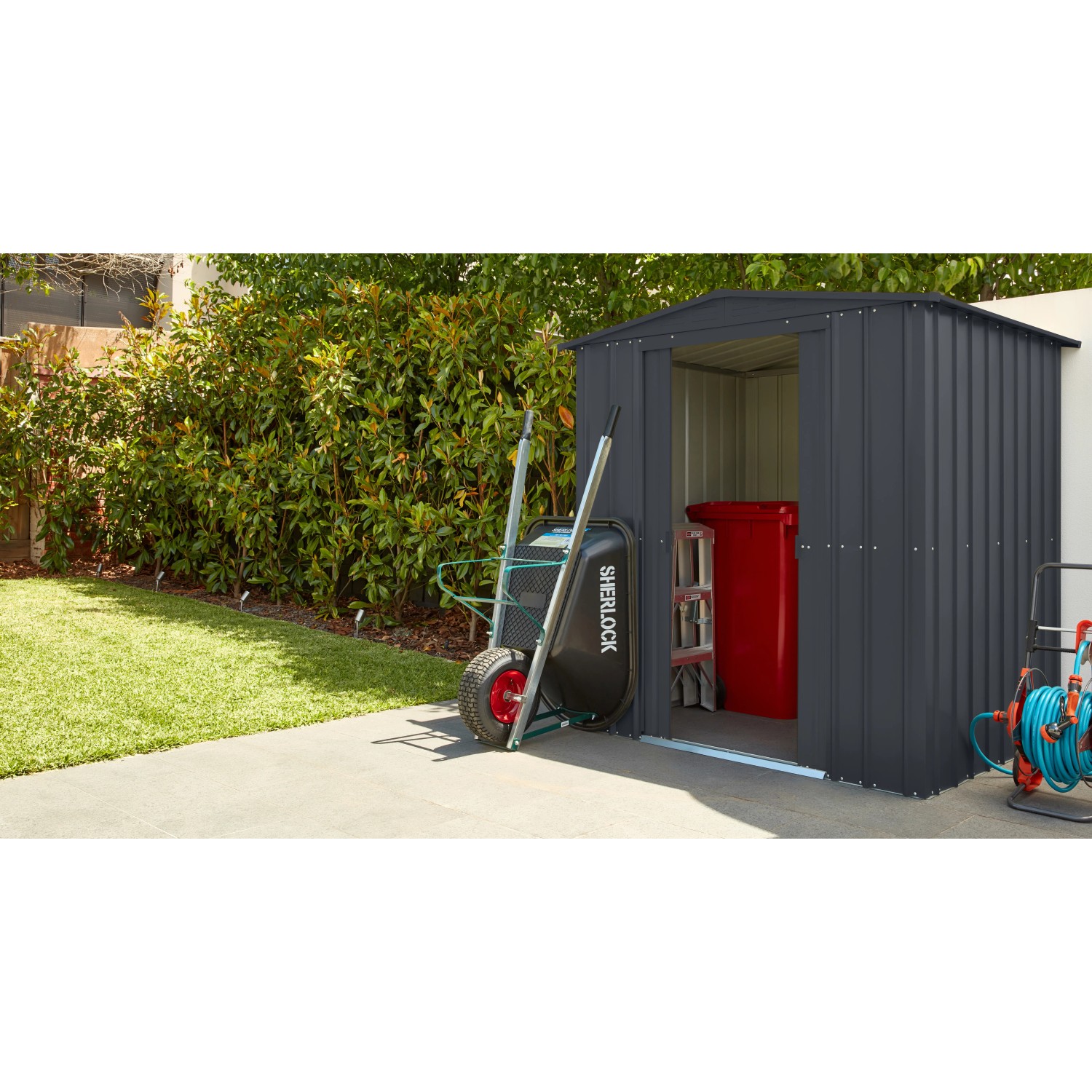 Globel Metall-Gerätehaus Dream 65 in Anthrazit mit Schubkarre und Gartenschlauch.