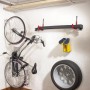 Montiertes Deckenhaken-System mit Fahrrad, Reifen und Gummistiefeln an der Wand.