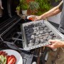 Char-Broil Gas2Coal 330 Kombigrill: Person legt Kohle in den Holzkohlegrill.