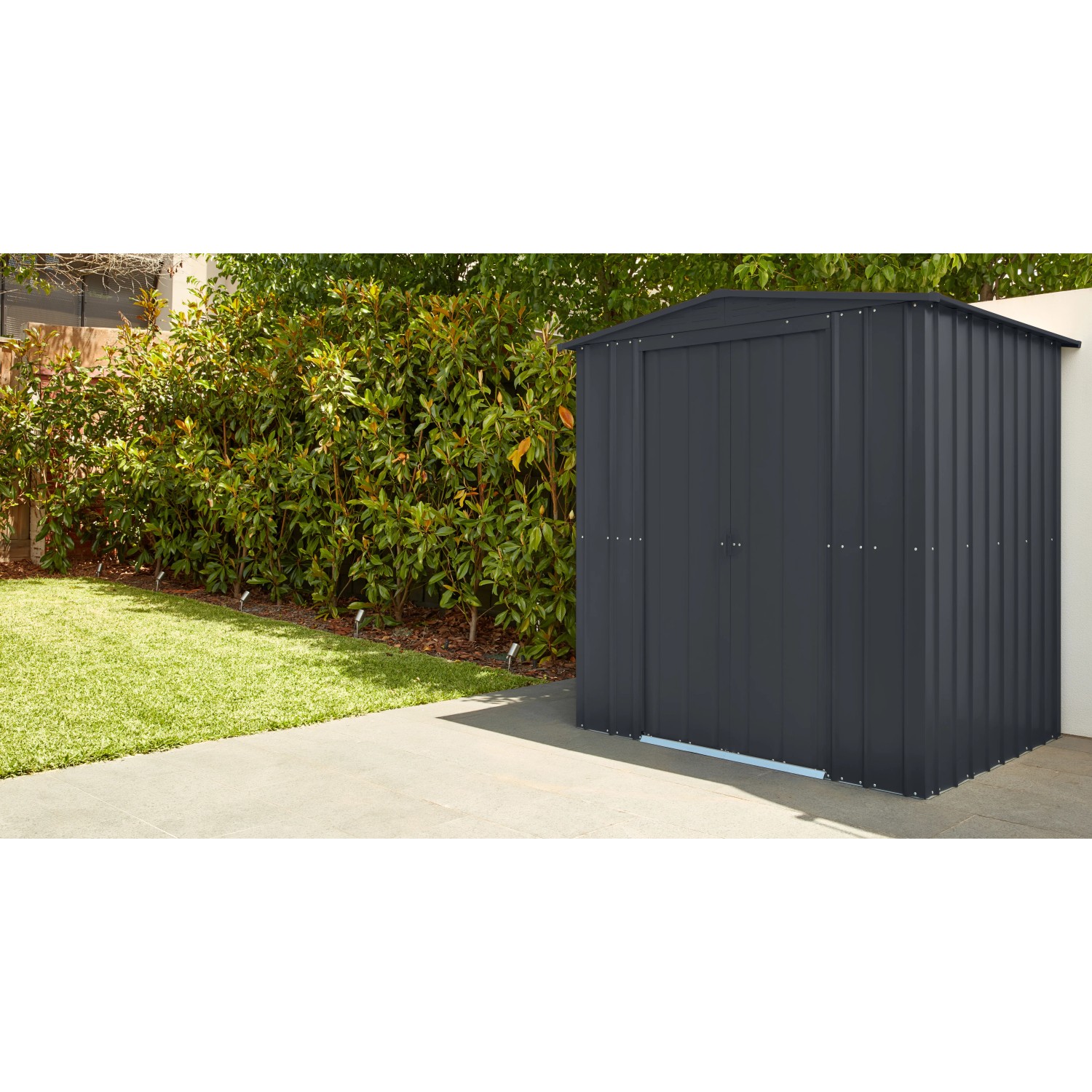 Globel Metall-Gerätehaus Gartenmanager Dream 65 in Anthrazit. Gerätehaus mit Doppeltür vor grüner Hecke.