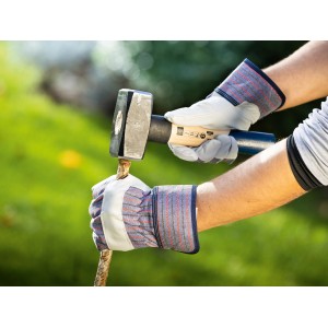 Hände mit Arbeitshandschuhen Gr. 8 beim Spalten von Holz mit einem Hammer.