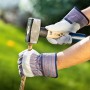 Hände mit Arbeitshandschuhen Gr. 8 beim Spalten von Holz mit einem Hammer.