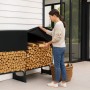 Frau lagert Holz in schwarzem osoltus Kaminholzregal aus Metall mit Abdeckung. Ideal für Brennholz-Lagerung im Außenbereich.