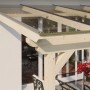 Skan Holz Terrassenüberdachung Ancona mit klarer Polycarbonat-Eindeckung und Holzpfosten.