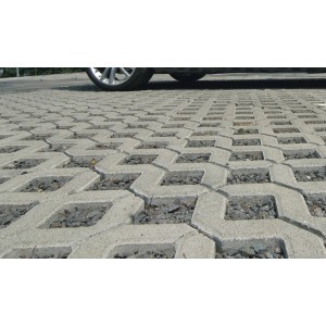 Graue Rasengittersteine aus Beton, verlegt mit Splittfüllung, befahren von einem Auto.