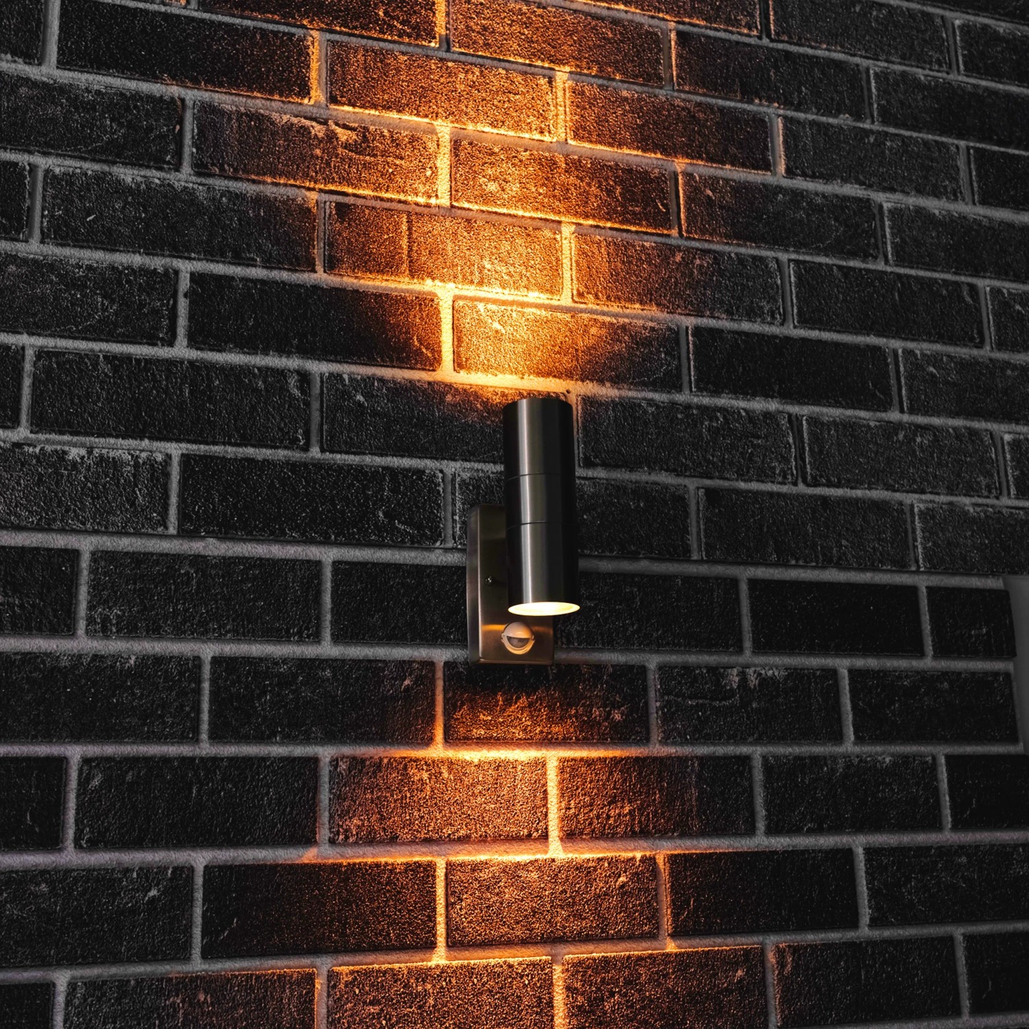 Moderne LED Außenleuchte aus Edelstahl mit IR-Sensor an einer Backsteinwand.