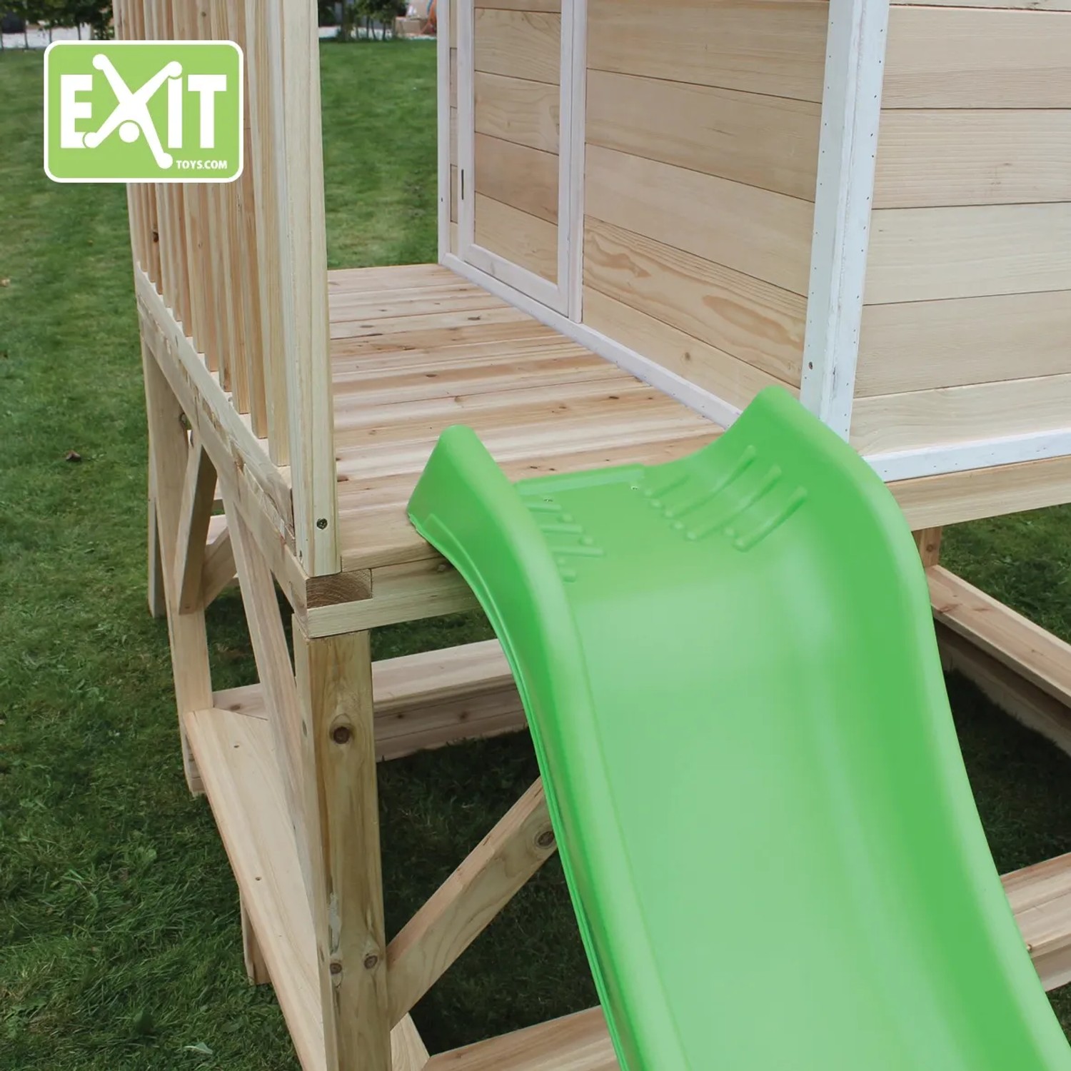 Detailansicht des EXIT Loft 500 Holzspielhauses mit grüner Rutsche und naturbelassenem Holz.