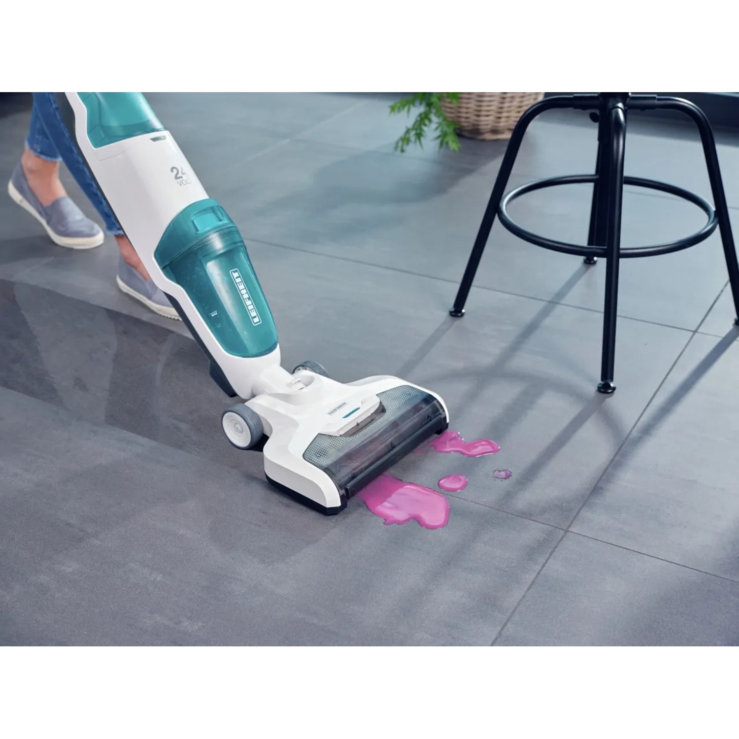 Leifheit Akku-Saugwischer Regulus Aqua PowerVac in Aktion, reinigt rosa Flüssigkeit auf Fliesen.