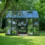 Häuschenförmiges, grünes Halls Gewächshaus Icon Planthouse 8 mit geöffneter Schiebetür im Garten.