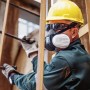 Handwerker mit Dräger Halbmaske X-plore 3300 (Gr. L) und gelbem Schutzhelm beim Arbeiten.