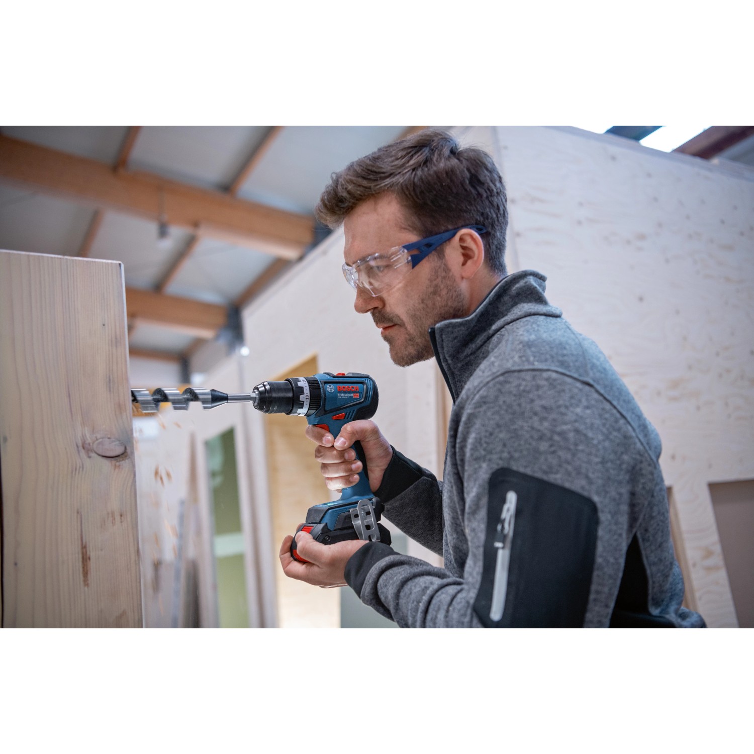 Mann bohrt mit Bosch Professional Akku-Schlagbohrschrauber GSB 18V-90 C in Holz.