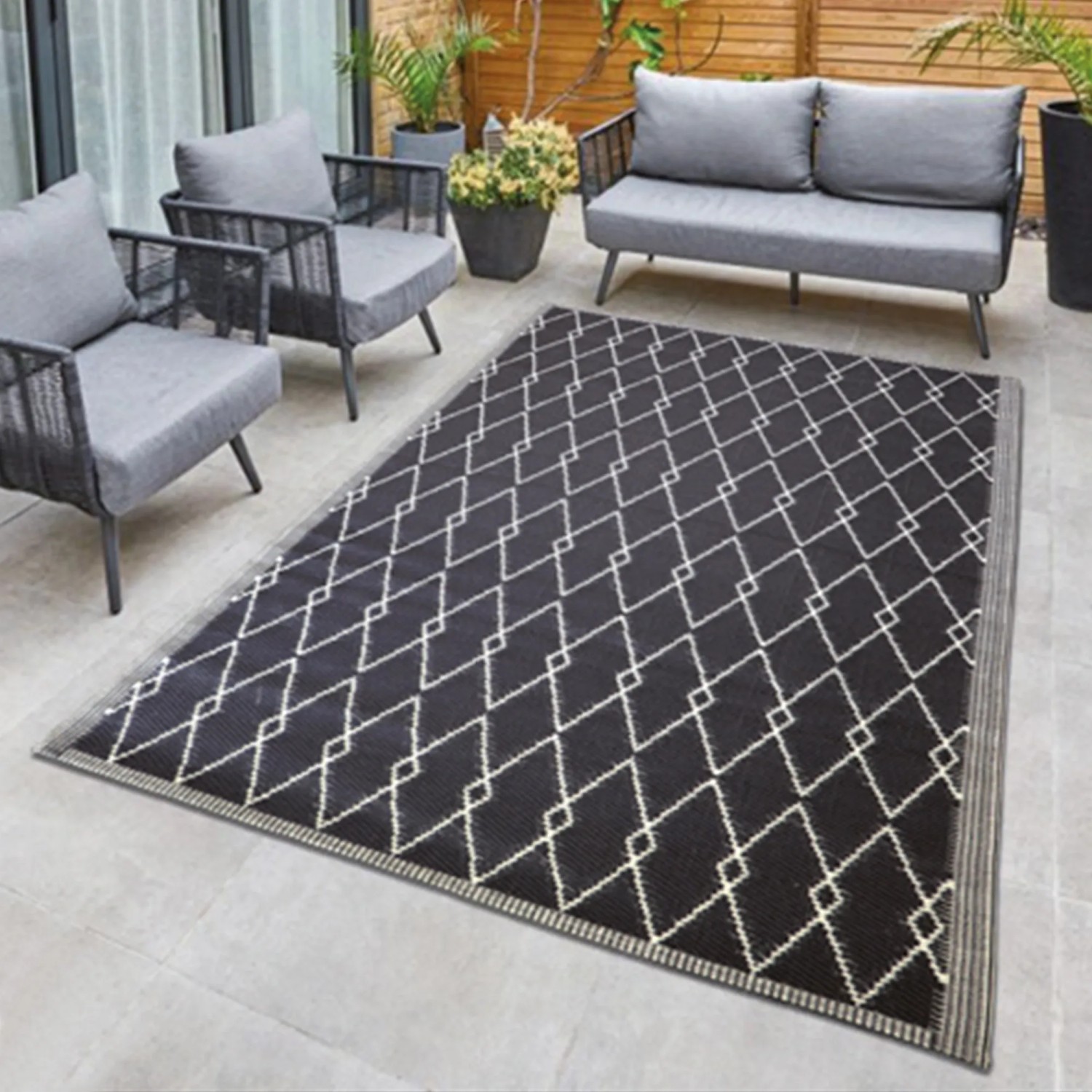 Bestlivings Outdoor-Teppich 160x230cm mit Rautenmuster auf Terrasse mit Gartenmöbeln.