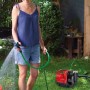 Frau bewässert Garten mit Einhell Hauswasserautomat GC-AW 6333. Elektro-Pumpe mit Schlauch.