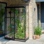 Schwarzes Halls Anlehngewächshaus Qube Lean-to 24 mit Pflanzen auf Terrasse.