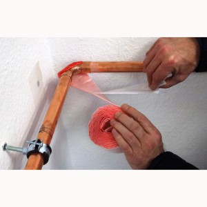 Rotes Scorprotect PE Wickelband mit Dampfsperre wird um ein Heizungsrohr gewickelt.