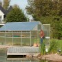 KGT Gewächshaus Alu blank 10 m² mit geöffneter Tür und Bepflanzung im Garten am Teich.