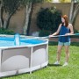 Frau reinigt Pool mit Intex Reinigungs-Set Deluxe, bestehend aus Kescher, Sauger und Teleskopstange.