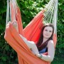 Frau entspannt in orangefarbenem AMANKA Hängesessel aus Baumwolle im Garten. Gemütlicher Schwebesessel für drinnen & draußen.
