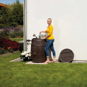 4Rain Regenfass Vino 250 l in Dunkelbraun Holzoptik mit Frau und Gießkanne.