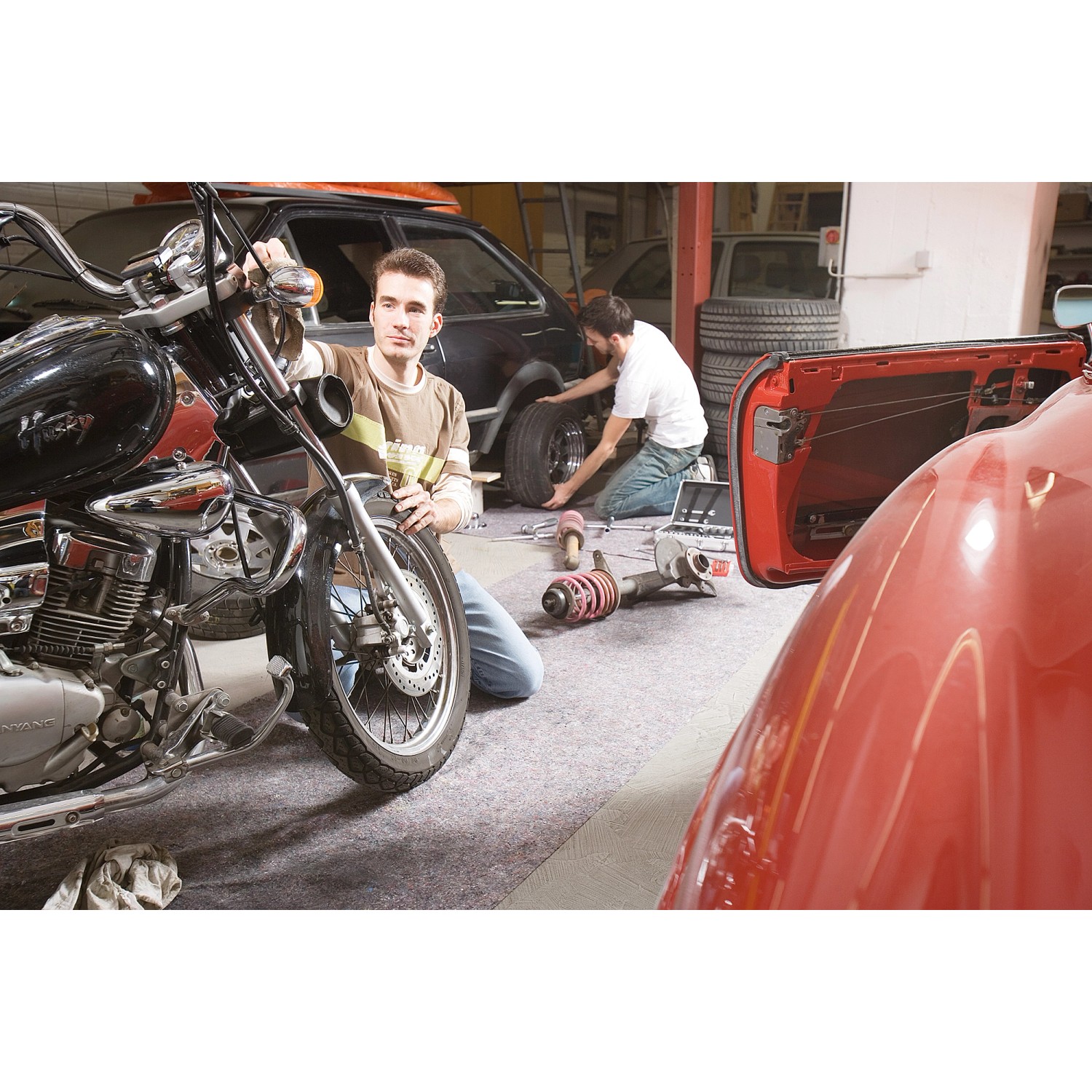 Werkstatt mit LUX Abdeckvlies: Motorrad, Auto und Mechaniker auf grauem Schutzvlies.