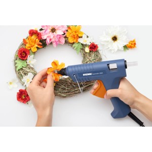 Steinel Heißklebepistole beim Anbringen von Blumen auf einem Kranz, mit transparenten Steinel Heißklebesticks.