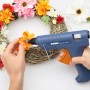 Steinel Heißklebepistole beim Anbringen von Blumen auf einem Kranz, mit transparenten Steinel Heißklebesticks.