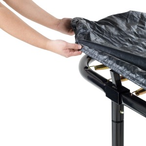 Schwarze EXIT Premium Abdeckplane für rechteckige Trampoline, hier beim Aufziehen auf das Trampolin.