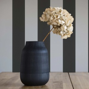 Tadessi Vliestapete mit schwarzen und hellgrauen Streifen an einer Wand, dekoriert mit Vase und Blume.