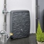 Anthrazitfarbene Waterform Regentonne Multitank 250 l mit Steinoptik und Wasserhahn neben Gießkanne.