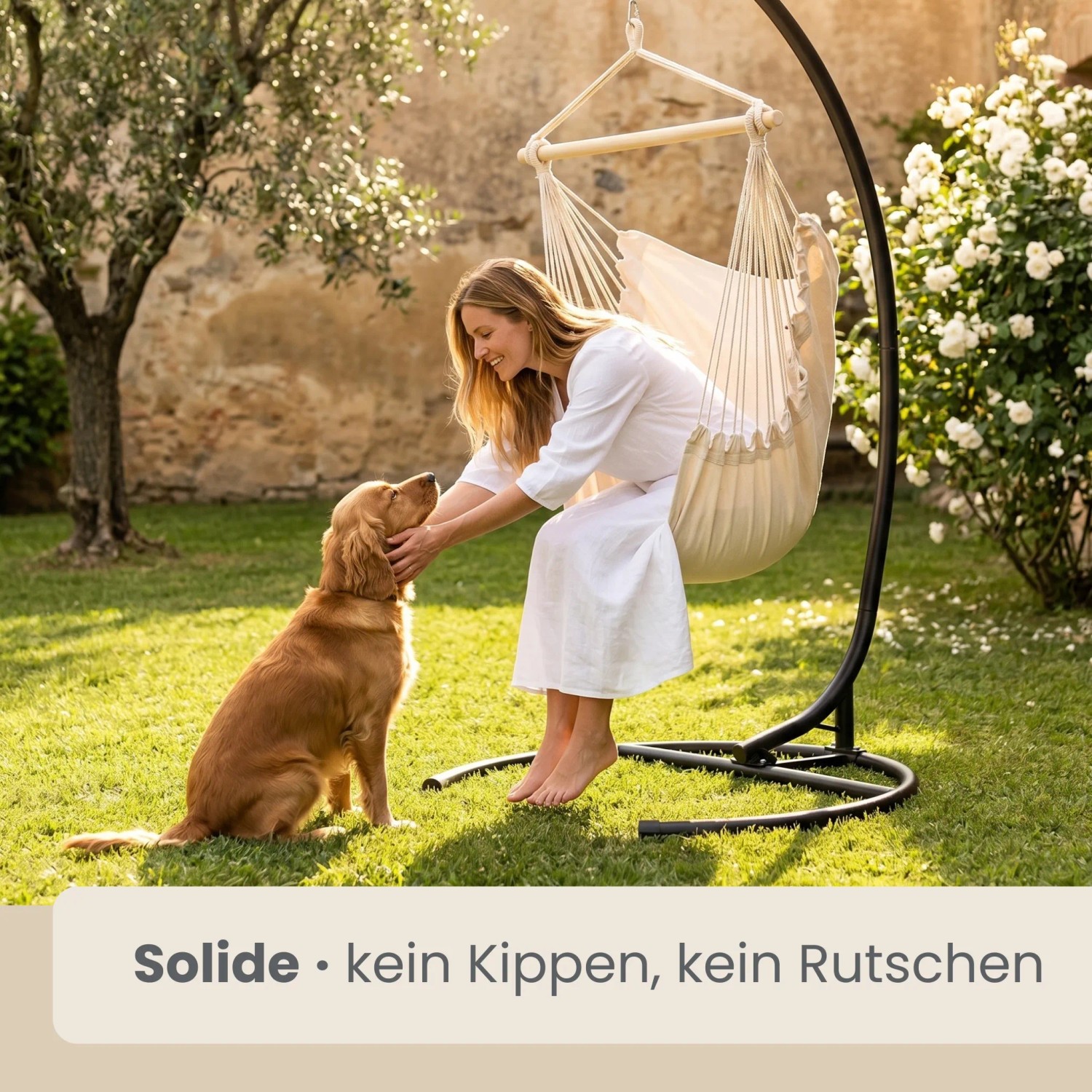 Schwarzes AMANKA Hängestuhlgestell im Garten. Frau entspannt im Hängesessel mit Hund. Robustes, standsicheres Gestell für Outdoor-Hängeschaukel.